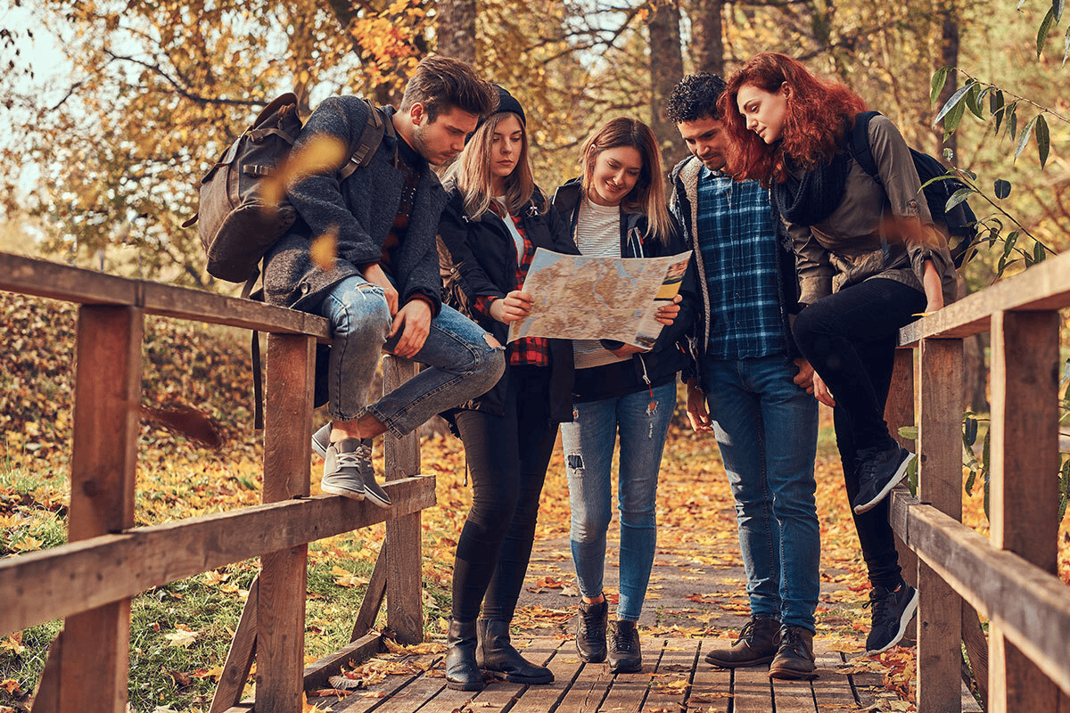 group of young people standing together on bridge outside looking at map