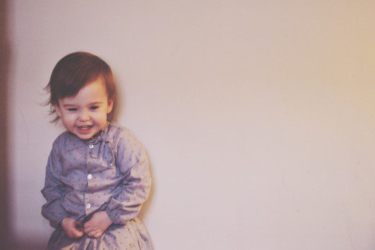young child in matching grey outfit laughing