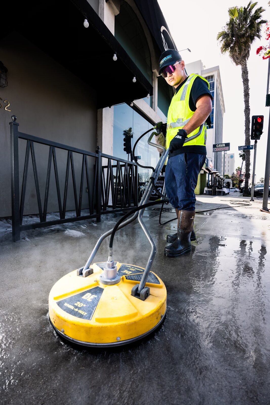 man cleaning pavements with machine wearing hi vis