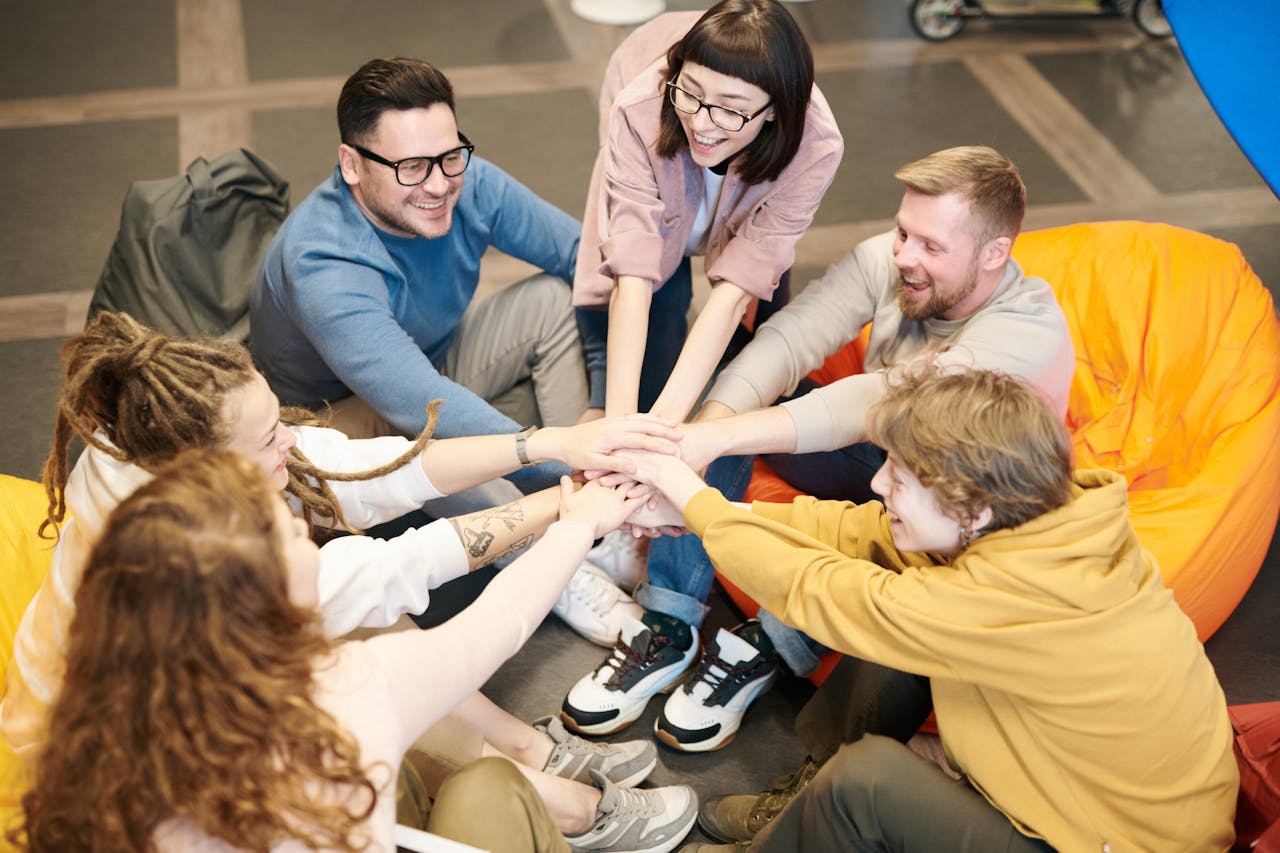 group of people with their hands one of top of the other in the centre of them all