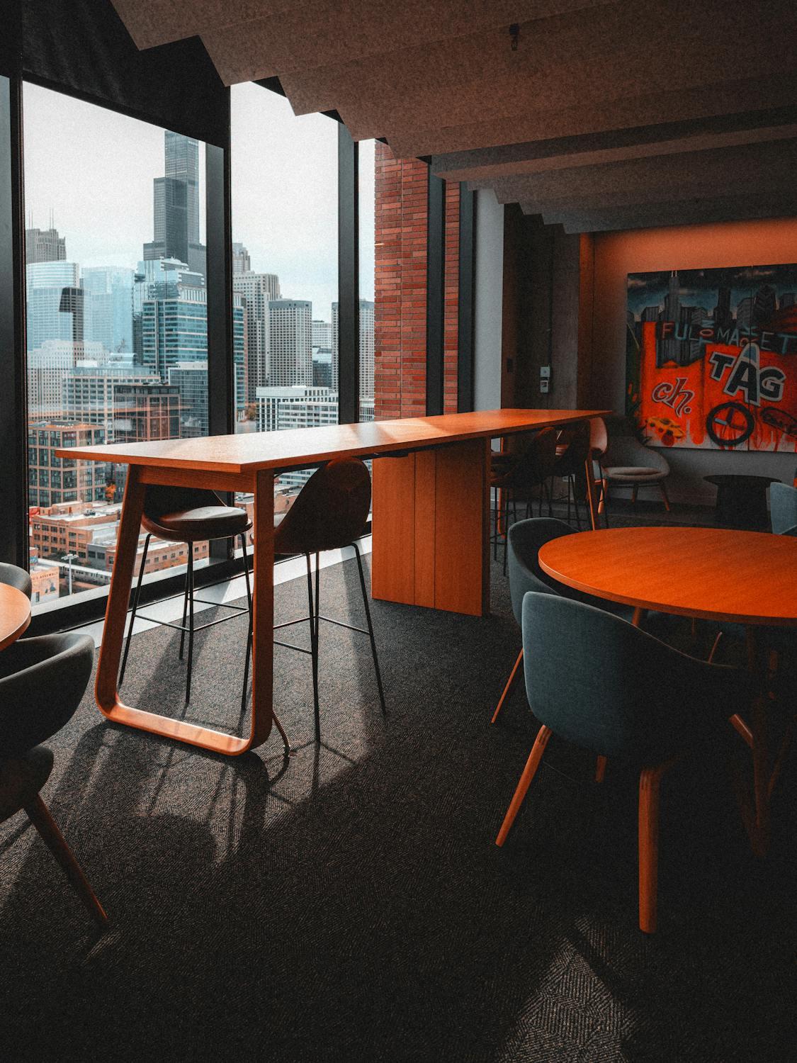 an office space with orange and navy furniture with ceiling to floor windows overlooking city