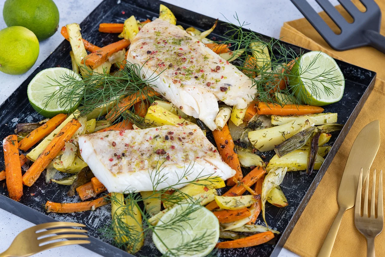 cod fish on top of colourful veg on baking tray before cooking