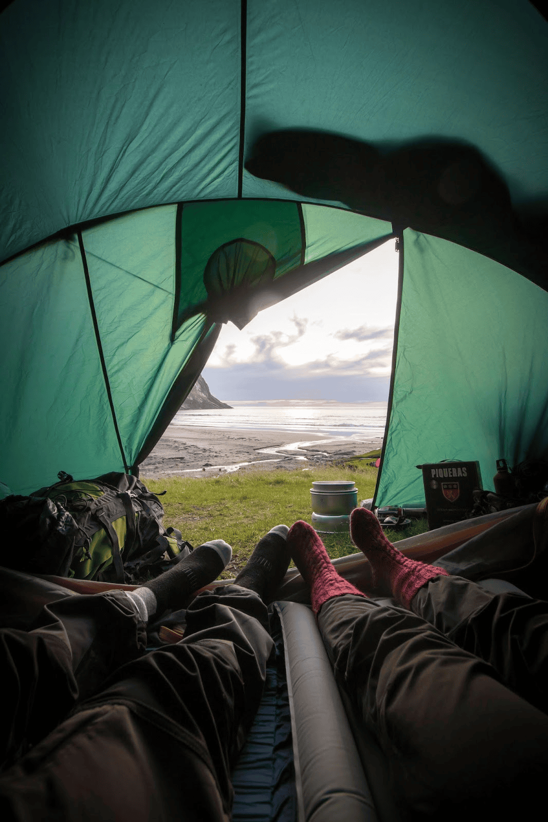 two people lying in a tent looking out onto beach