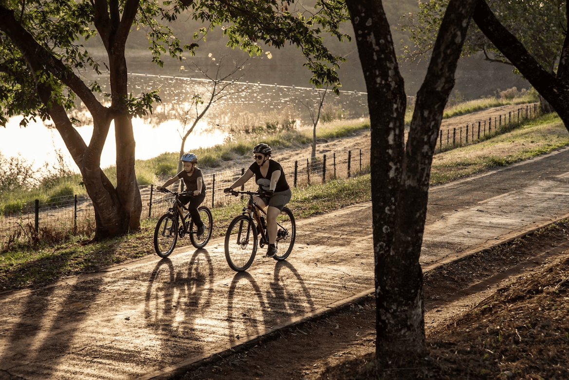 adult and child riding bikes along path next to trees and lake