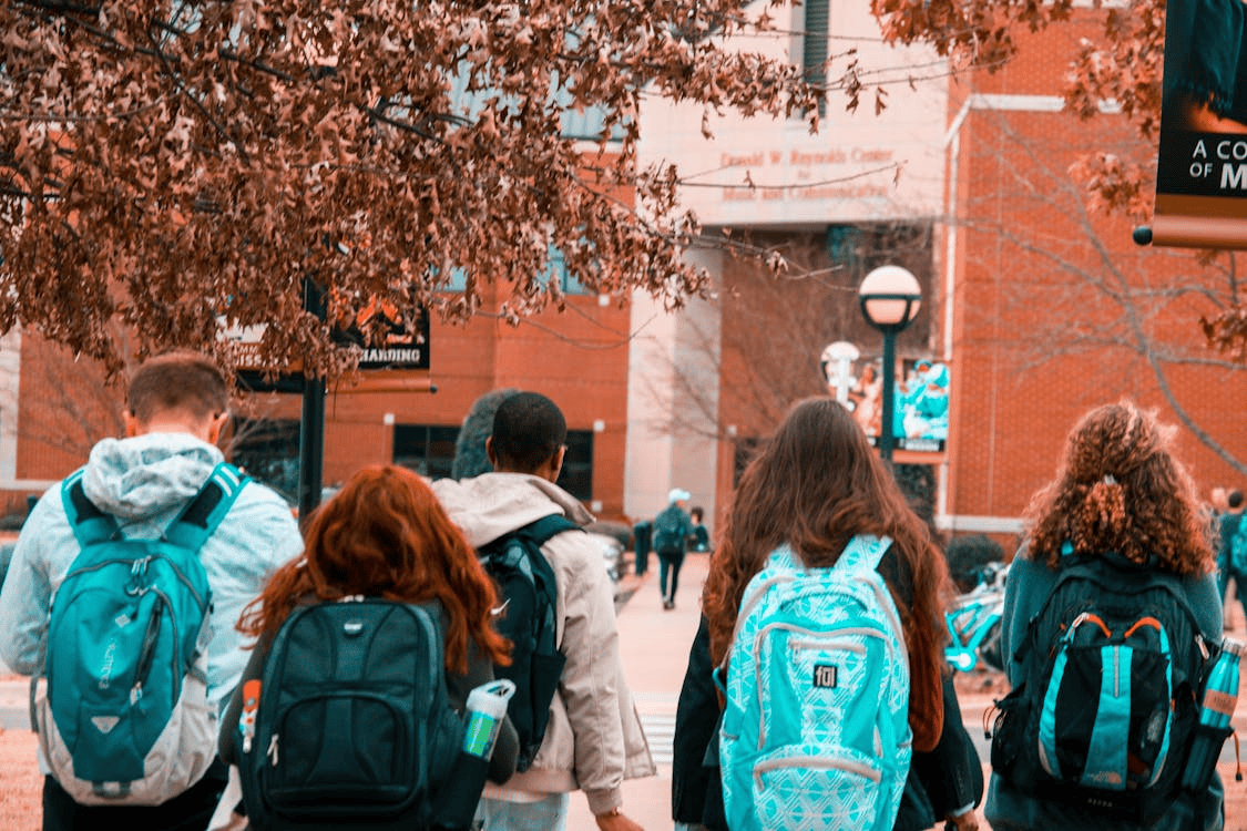 teenagers waring backpacks walking into school