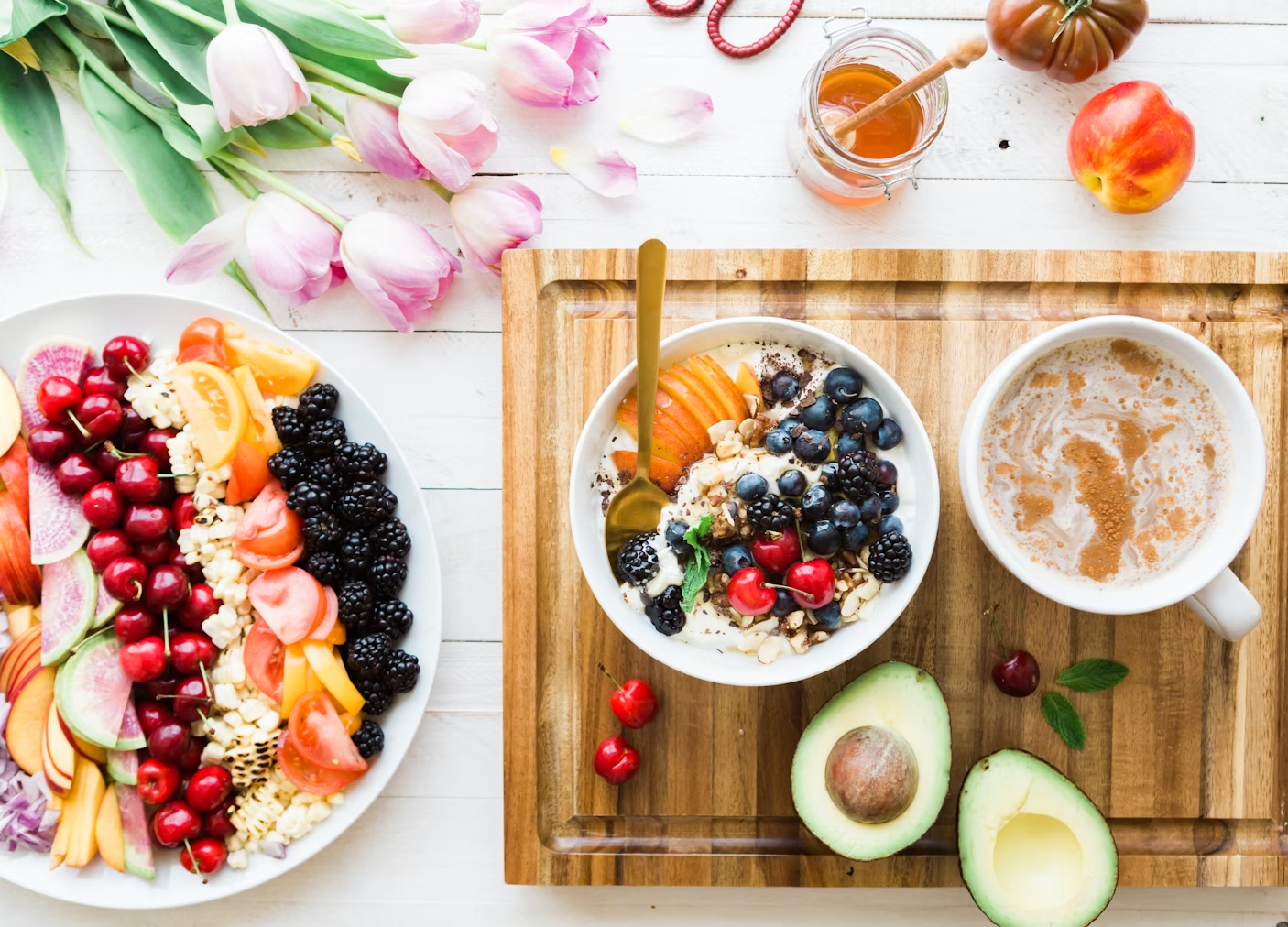 aerial view of bowls of healthhy food, with fruit, avocado, honey in pots