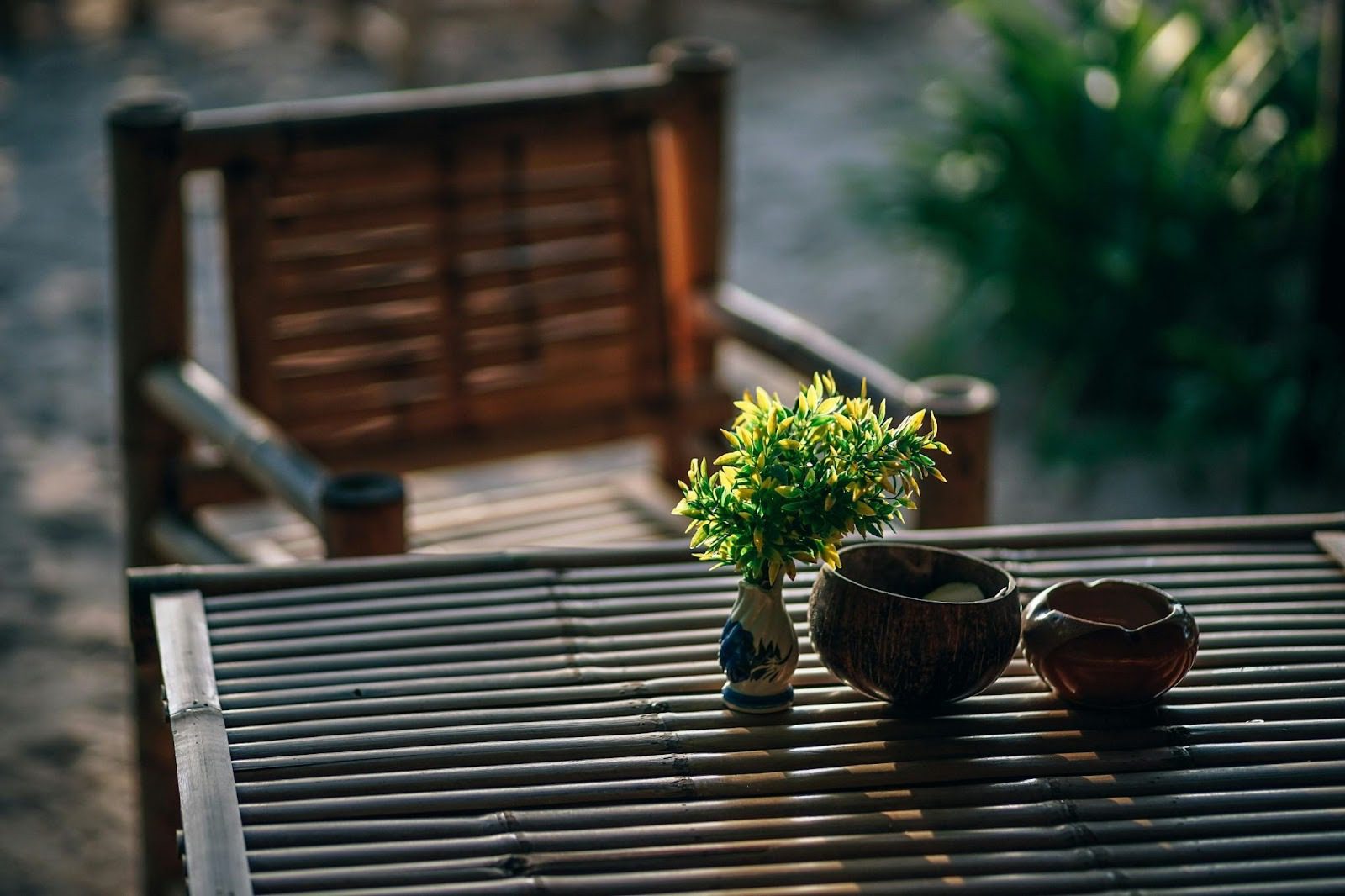 bamboo wooden table and chair outside with plant and bowls on