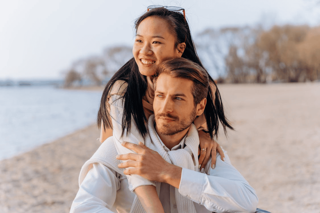 smiling woman on man's back on the beach