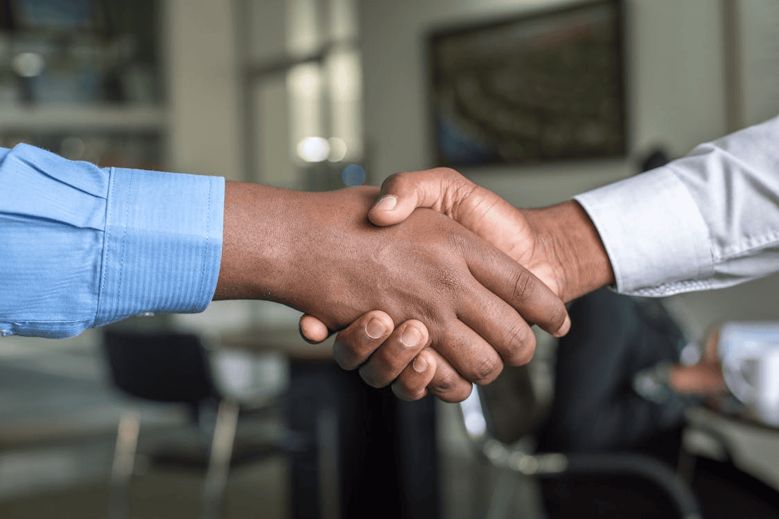 two people wearing shirts shaking hands