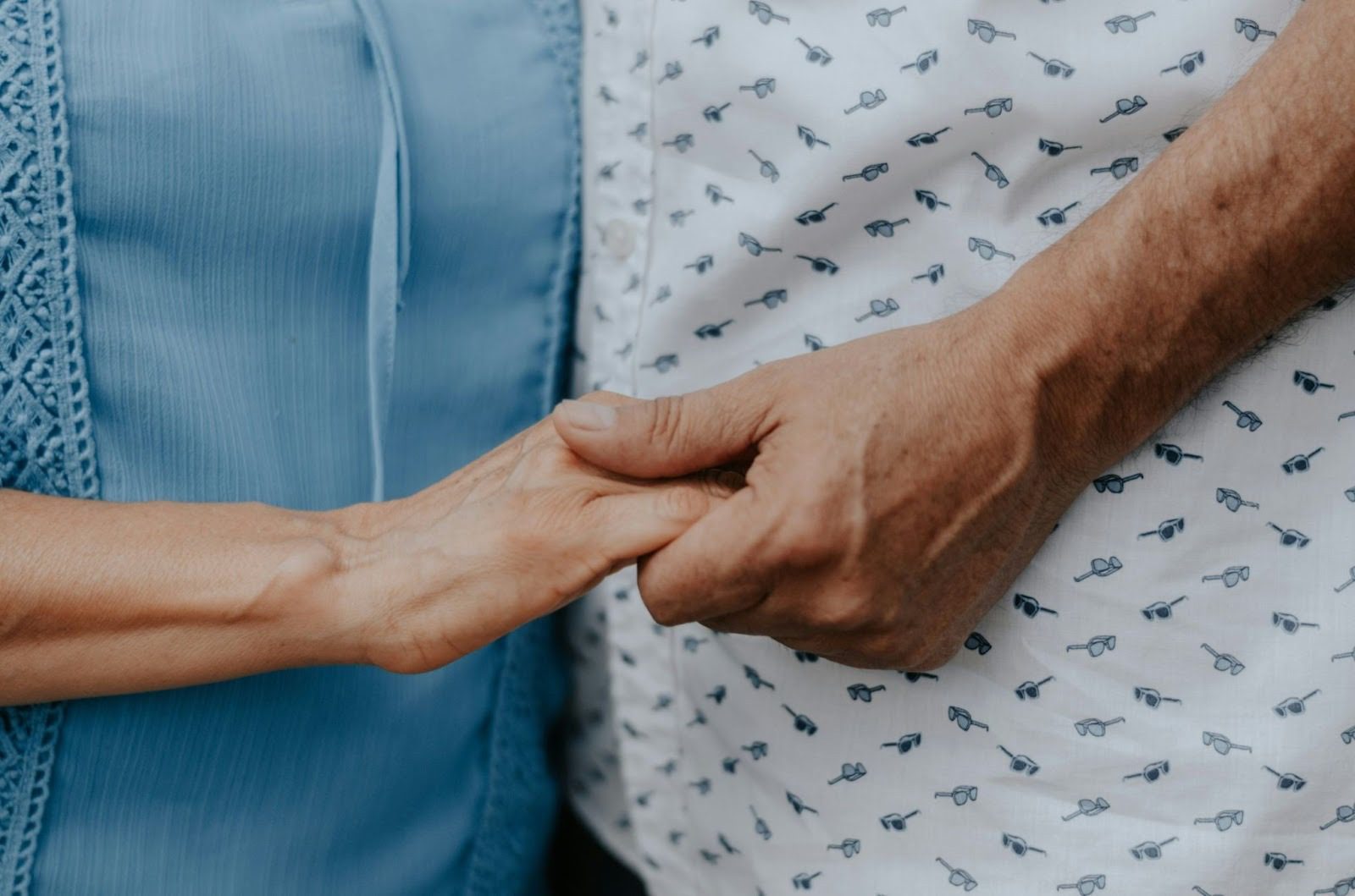 two old people close up holding hands
