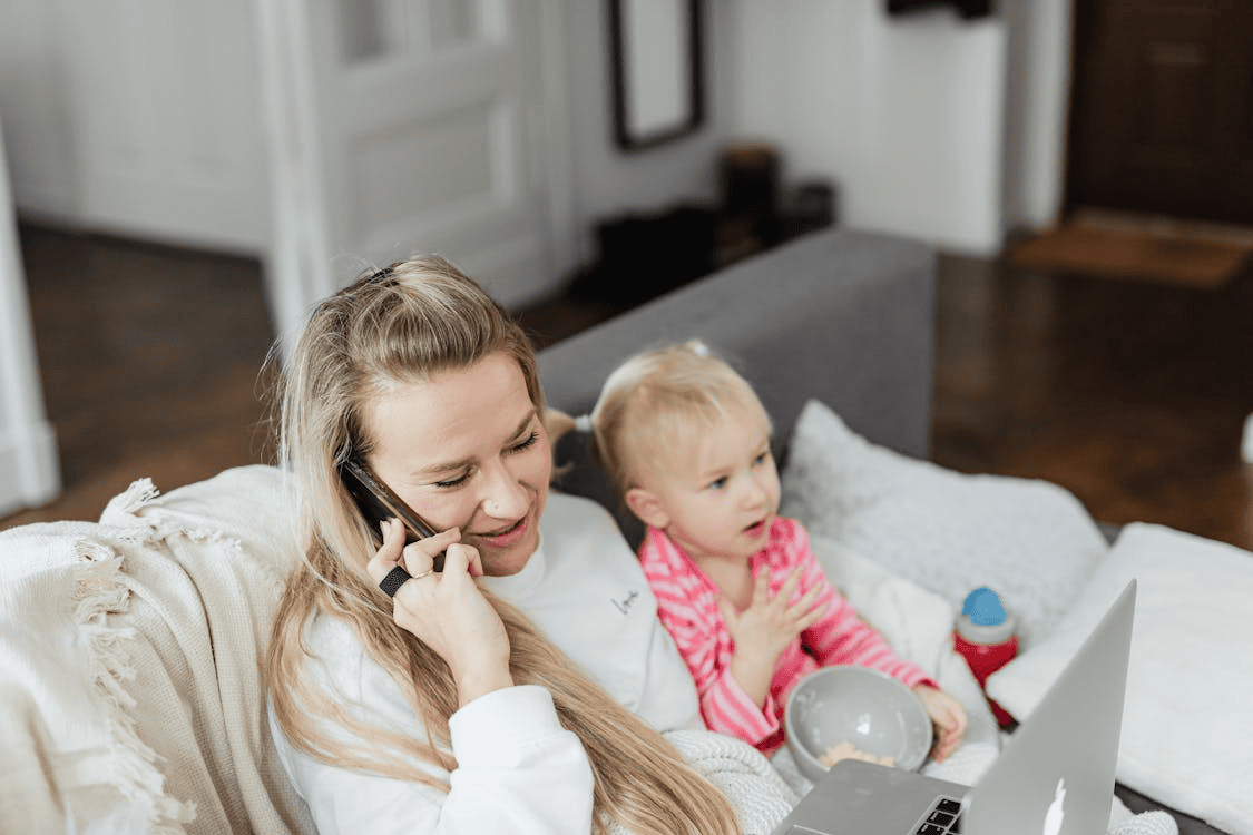 mother on phone, sitting with child on sofa