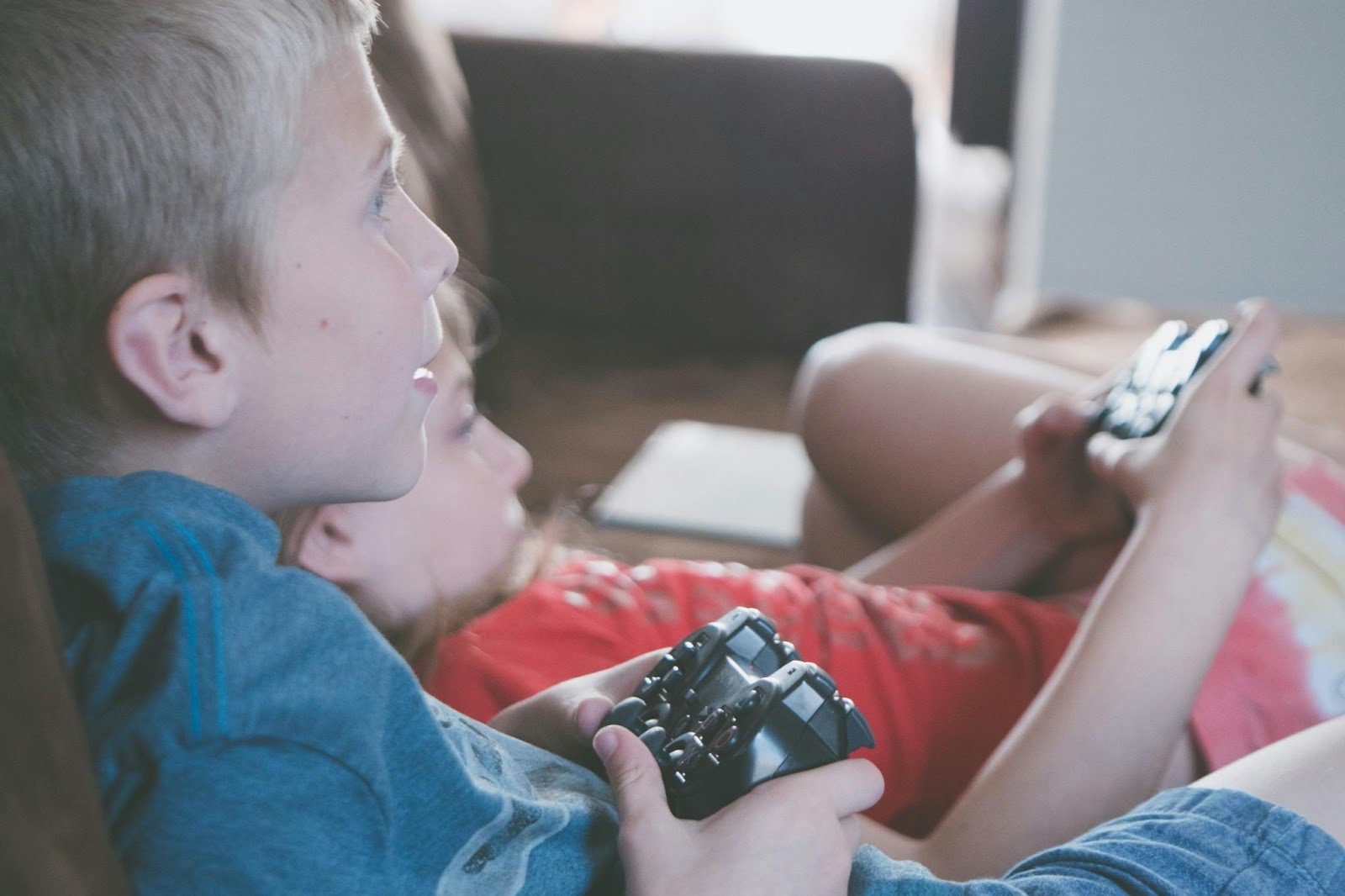 two children lying on the floor holding video game controls