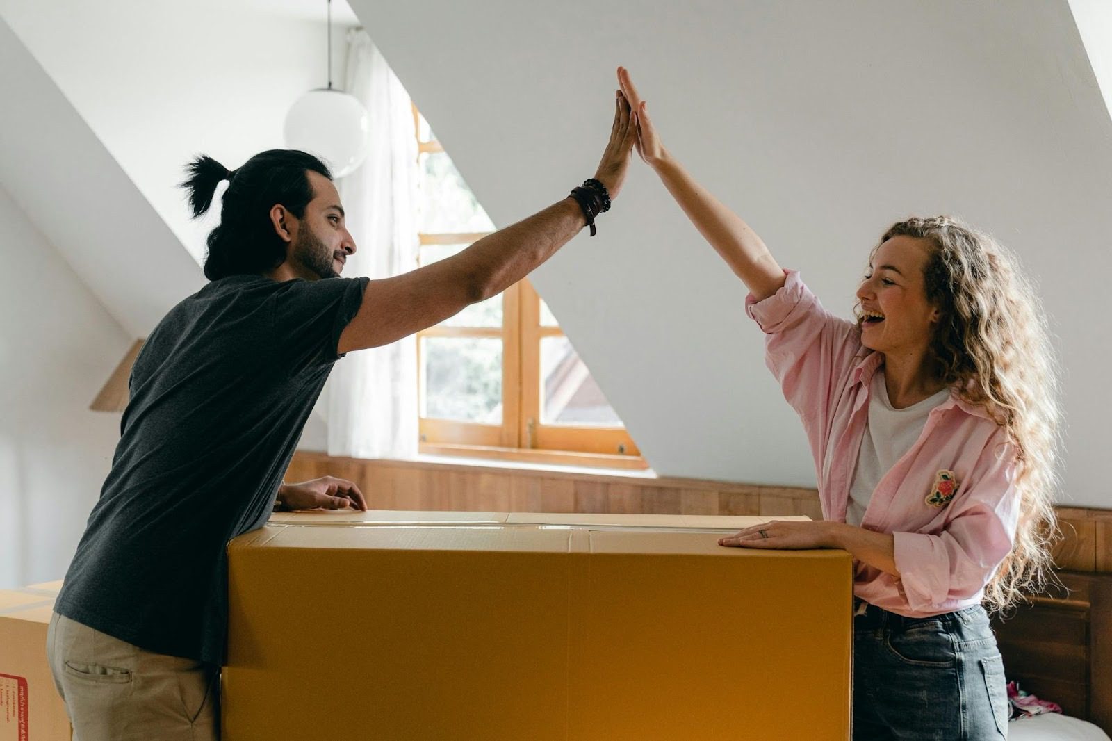 man and woman high-fiving over large box in home