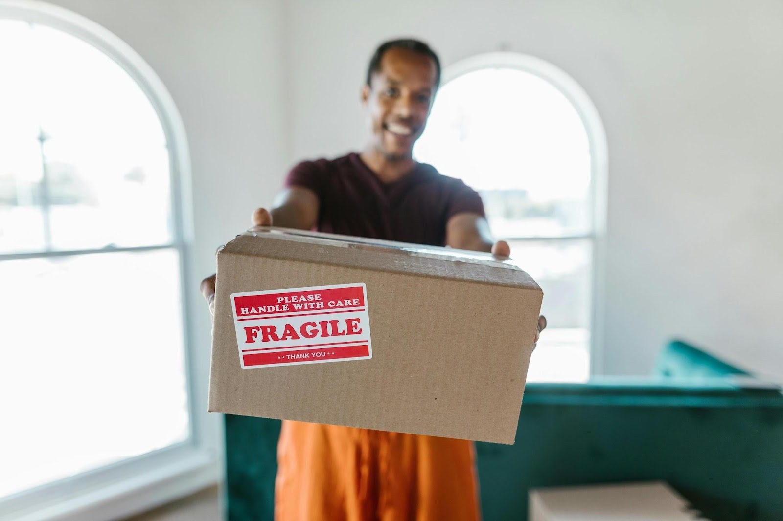 man smiling and holding packing box with fragile sticker on it