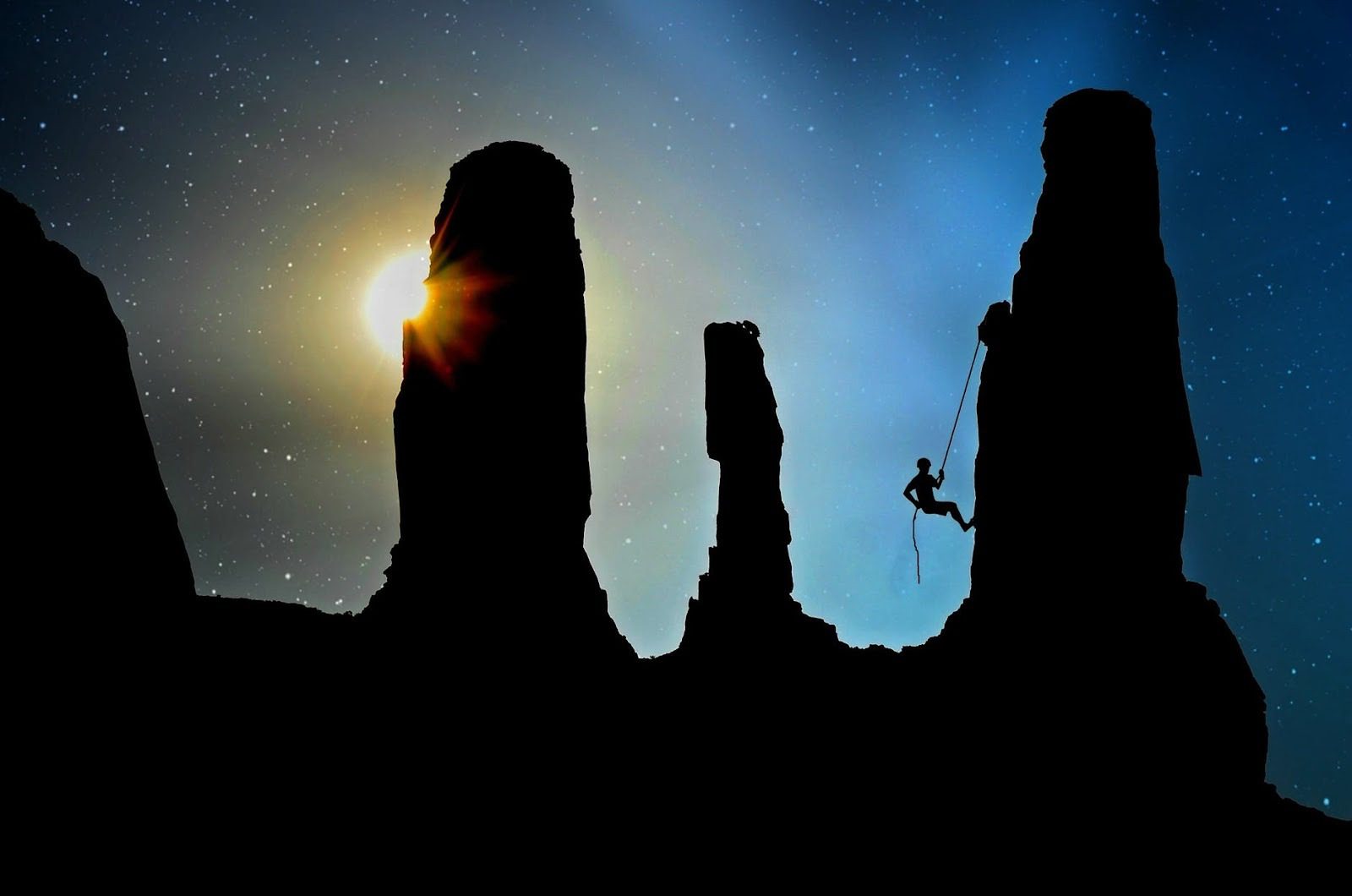 view of large rocks in the dark with someone climbing up on of them