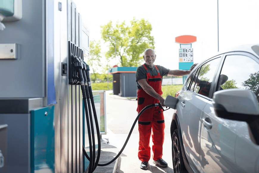 man in red overalls putting petrol into car