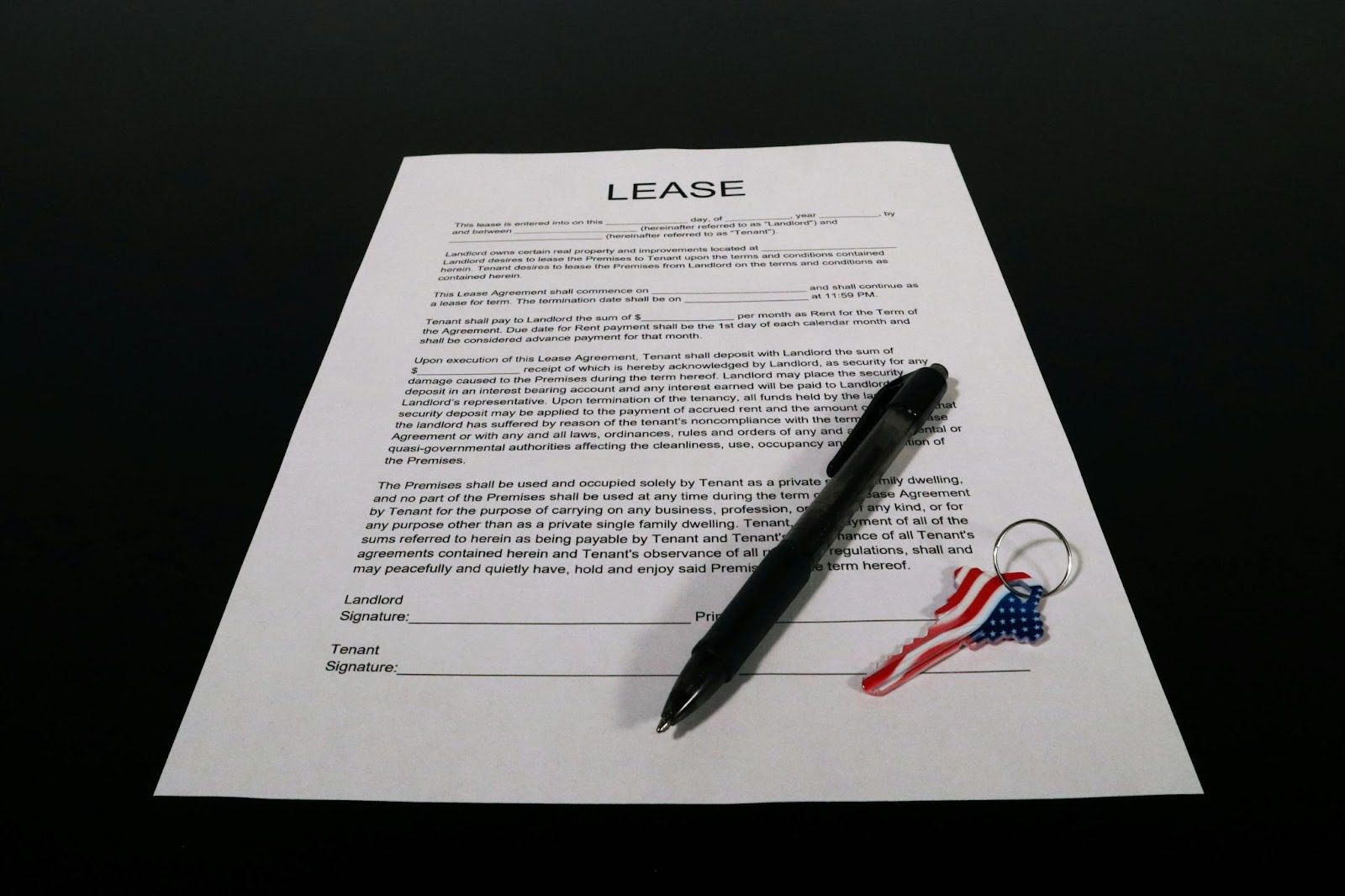 piece of paper on black surface, with black pen and US keyring on it, with LEASE written at the top