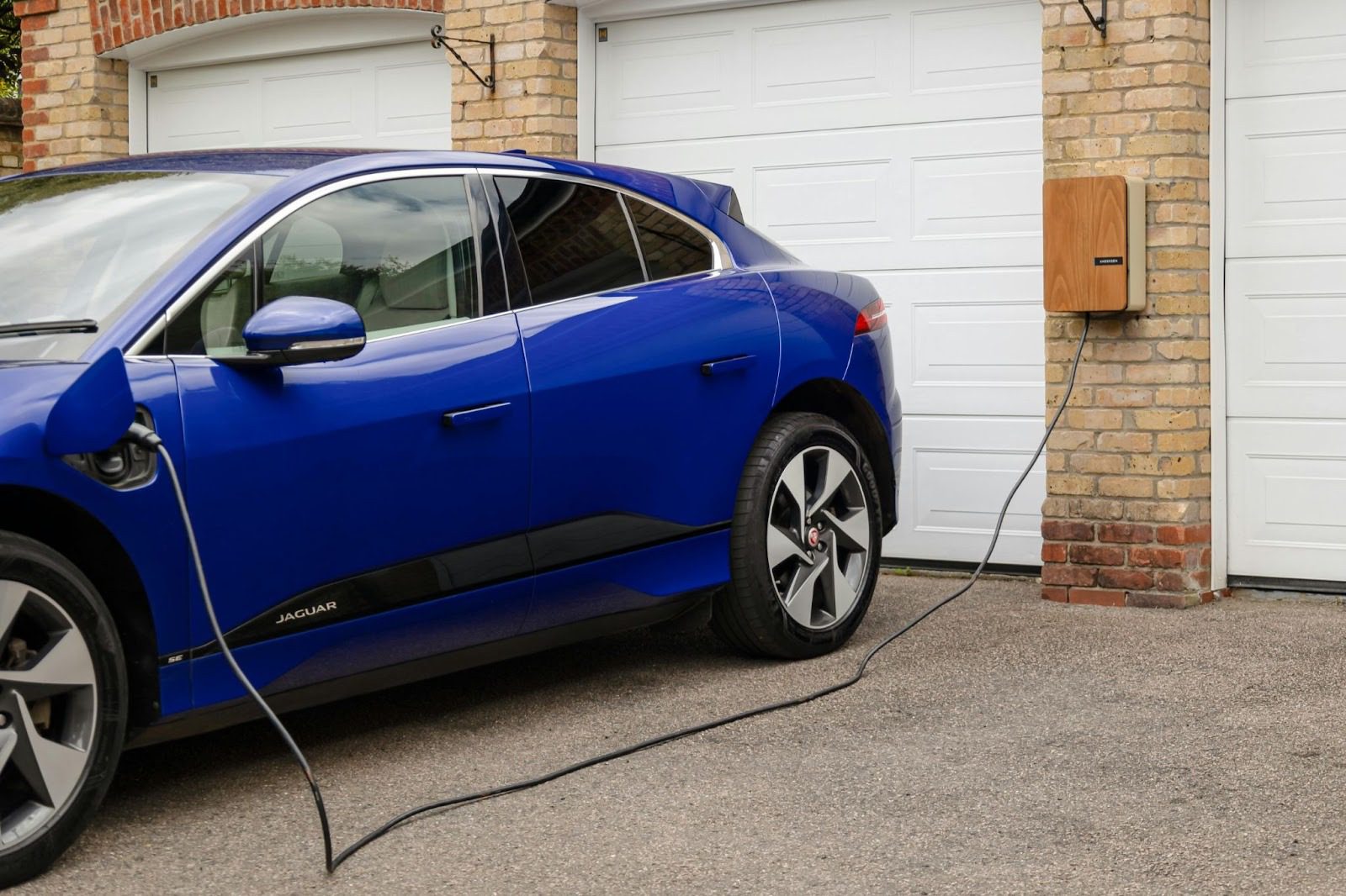 blue car plugged into electric charger outside home