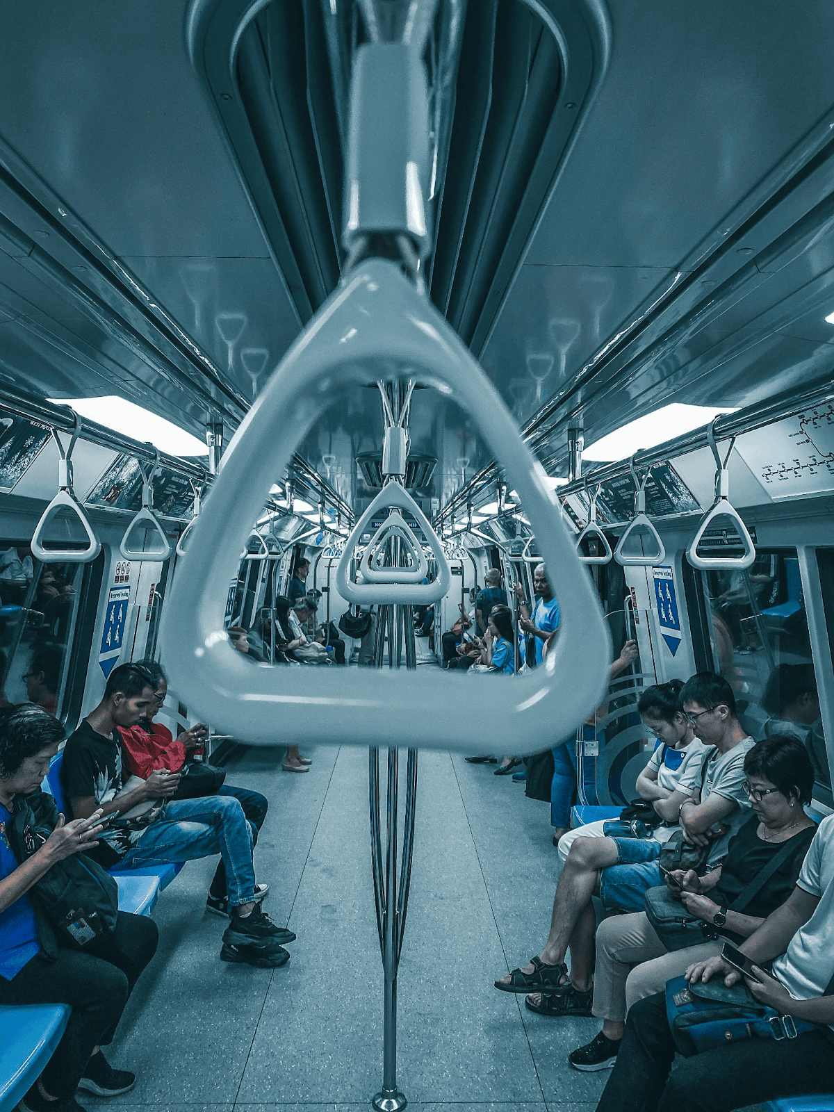people seated along either side of a tube, some looking at their phones