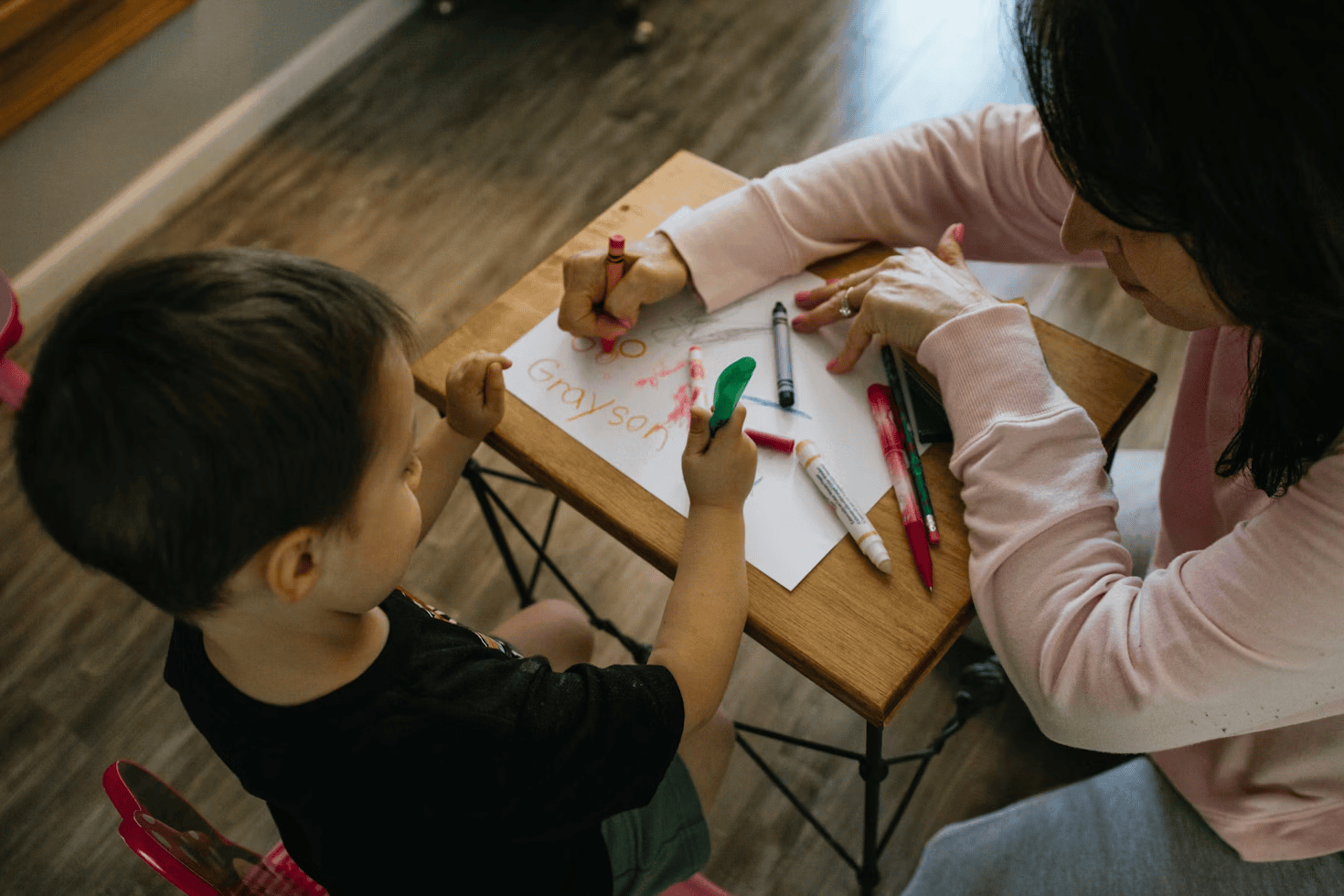 woman and child sitting at table colouring