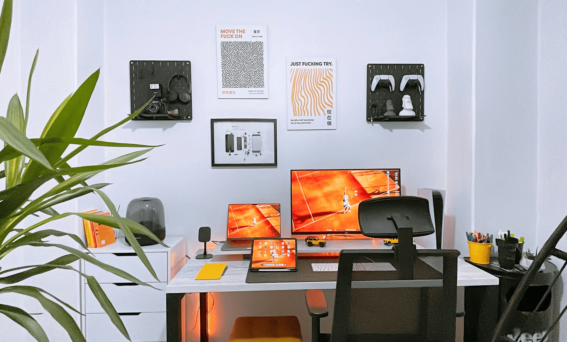 home office with three screems, a large plant and art on walls