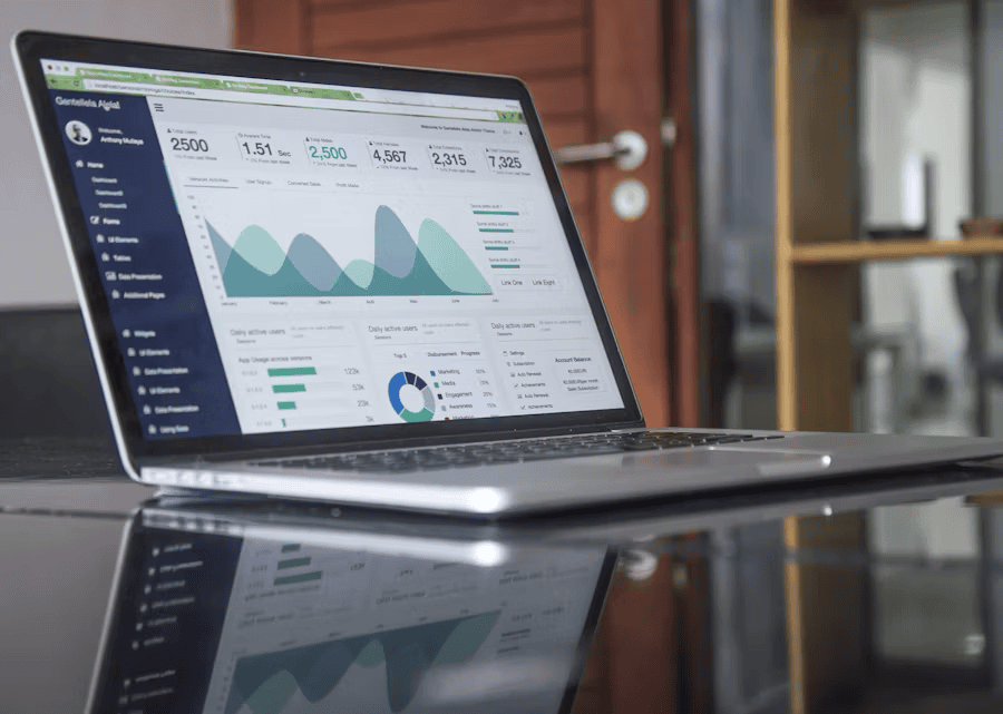 open laptop on desk with charts and stats on screen