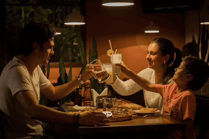 family sat at table for meal, cheers-ing with their drinks