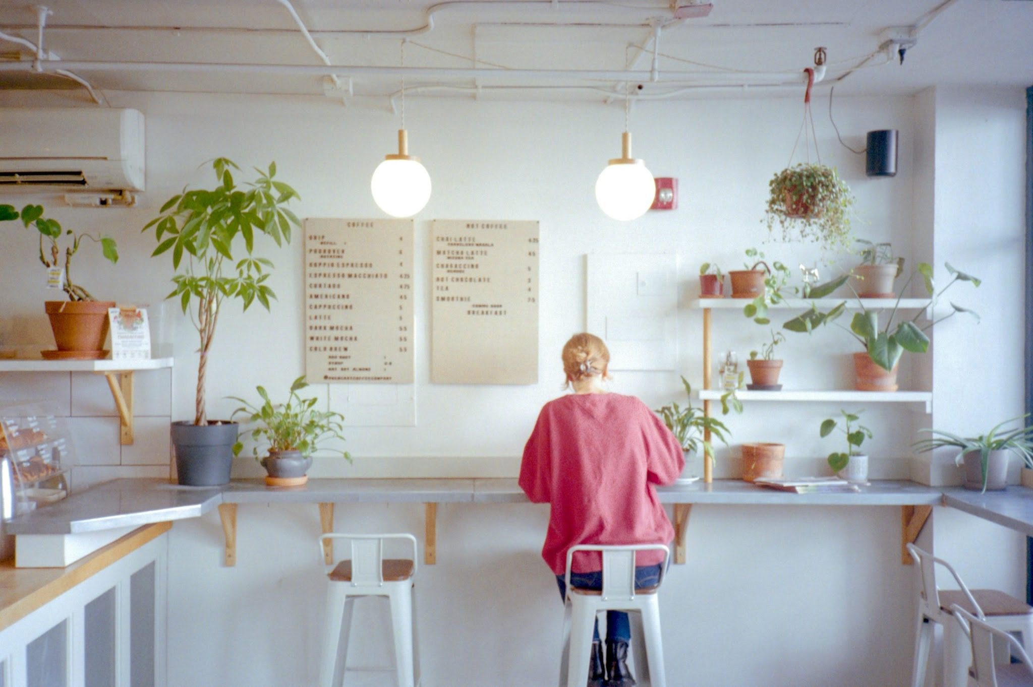 woman sitting on high stool at bar table in cafe