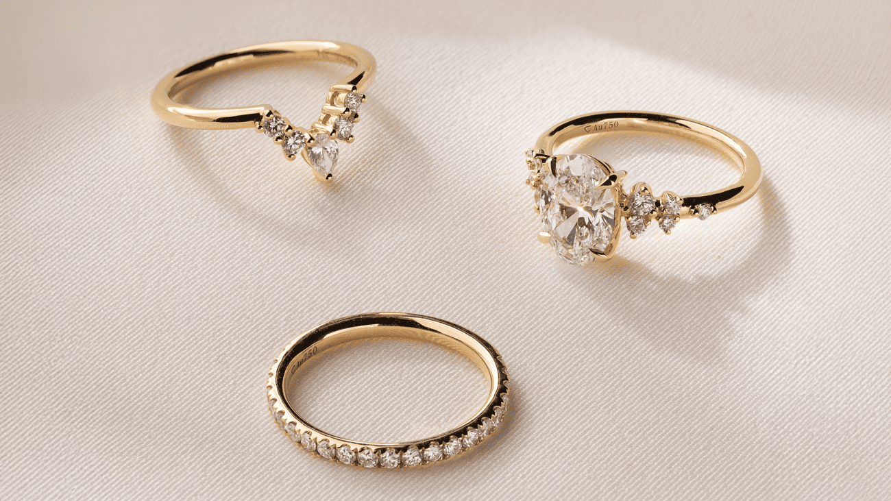 three gold and diamond rings on flat surface
