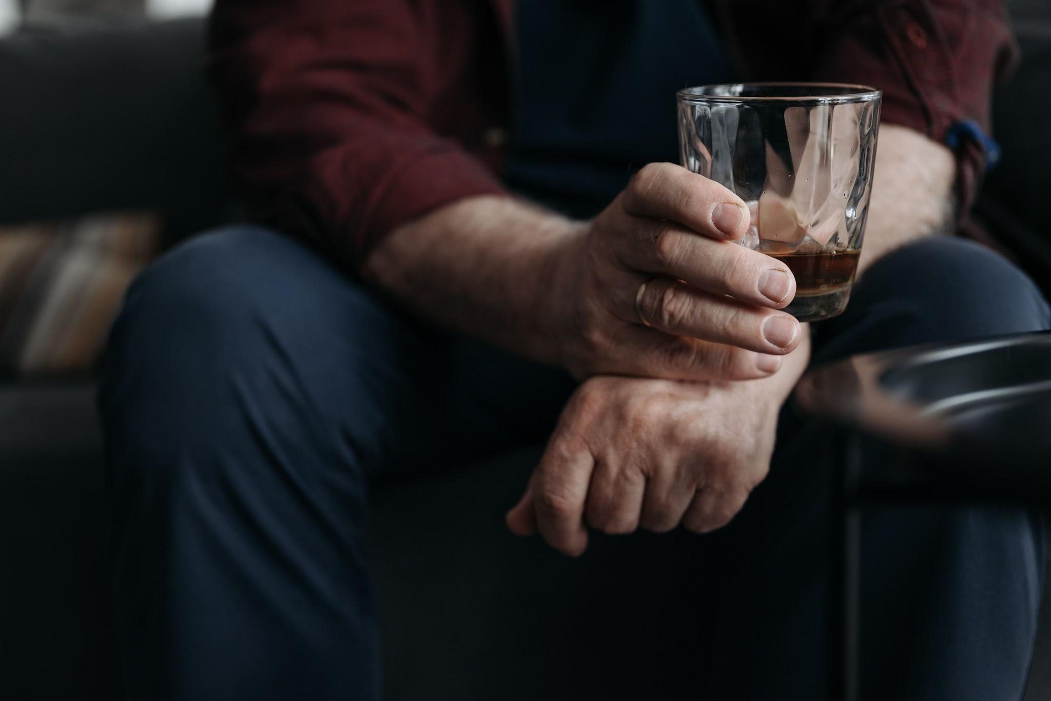 man sitting on sofa holding a glass of alcoholic drink
