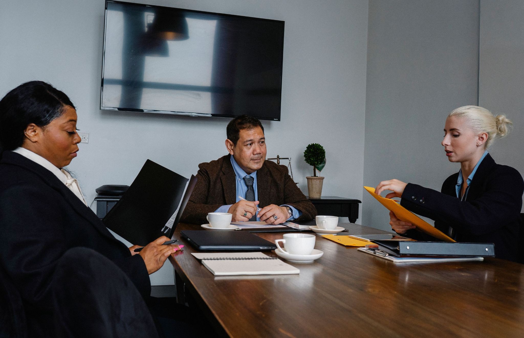 3 people sat around desk in business meeting